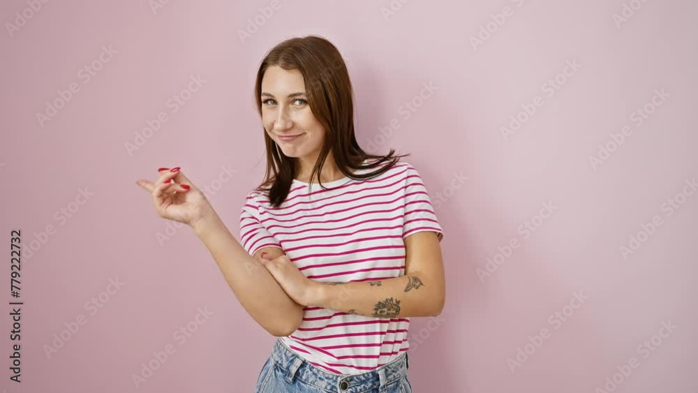 Happy young brunette in striped t-shirt, pointing to side with trusting smile, looking at camera over pink isolated background - welcoming gesture, perfect for products advertisments! Happy young brunette in striped t-shirt, pointing to side with trusting smile, looking at camera over pink isolated background - welcoming gesture, perfect for products advertisments!