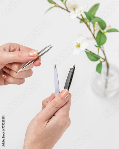 Woman holding assortment of tweezers and manicure tools in trendy bathroom