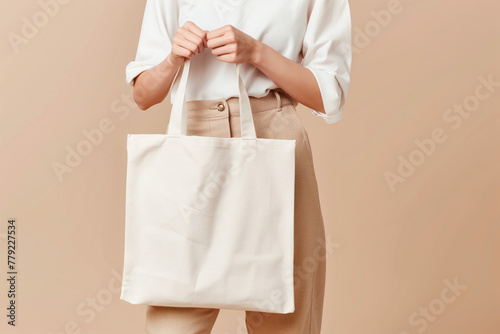 Woman holding eco friendly white hand bag with empty white space for advertisement. Mockup bag.  © Koray
