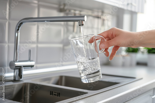 A person is filling a glass with water from a faucet. Concept of simplicity and routine, as the act of filling a glass with water is a basic and everyday task. The focus on the person's hand
