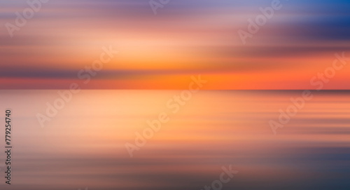 Abstract sun is setting over the ocean  casting warm glow on water. The sky is filled with clouds  creating a moody atmosphere. reflection of sun on water is a beautiful sight to behold  motion blur.