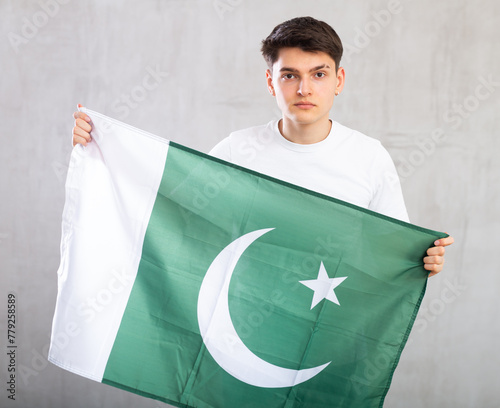 Portrait of calm, friendly middle-aged male businessman with national flag of Pakistan. Studio shot, gray background, modern up-to-date content