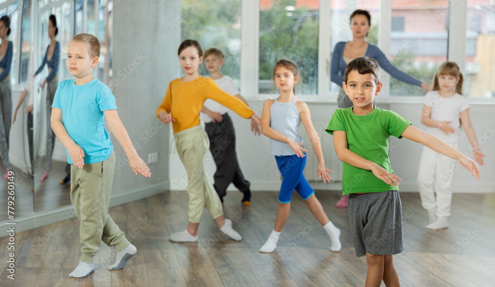 Children training modern dance moves together in studio under the guidance of a teacher