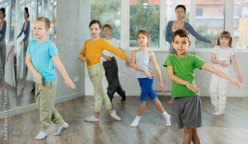 Children training modern dance moves together in studio under the guidance of a teacher