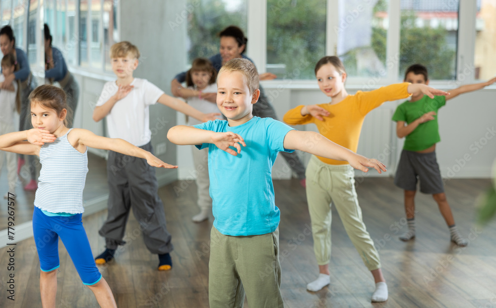 Group of preteen girls and boys enjoying active dance movement in modern studio