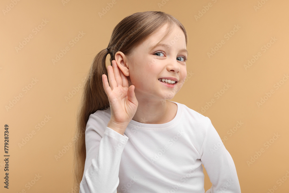 Little girl with hearing problem on pale brown background Little girl with hearing problem on pale brown background