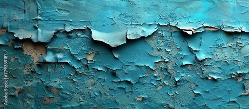 Close up view of peeling blue paint chipping off the surface of a weathered concrete wall, revealing the raw texture underneath photo