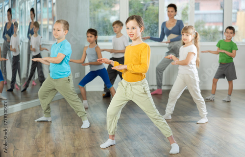 Group of happy preteen children with female teacher practicing hip hop in modern dance studio