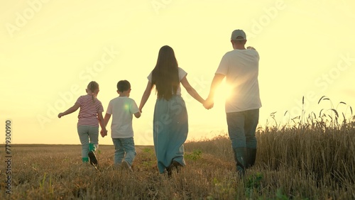 Son daughter dad mom walk hand in hand in child. Happy family of farmers with children walks through wheat field, sunset. Big family, group of people in nature. Childrens dream, complete family, kids