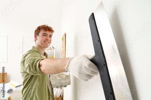 Young man with putty knife ...