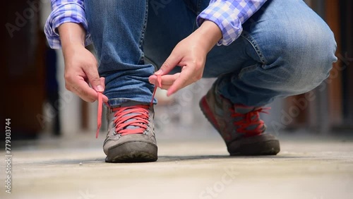 Man kneels down rope tie shoes industry boots for worker. Close up shot of man hands tied shoestring for his brown construction boots. Close-up man hands tie up shoes for footwear concept.