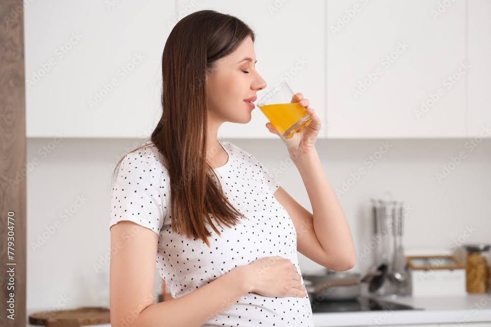 Beautiful pregnant woman drinking juice in kitchen Beautiful pregnant woman drinking juice in kitchen