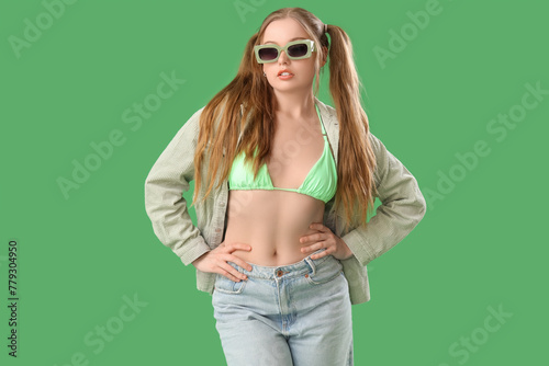 Beautiful young woman in stylish outfit on green background © Pixel-Shot