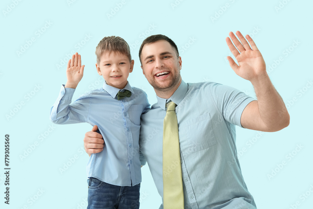 Happy father and his little son waving hand on blue background Happy father and his little son waving hand on blue background