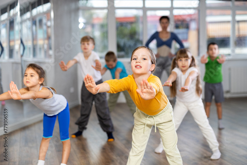 Group of boys and girls with teacher doing warm-up exercises before dancing in studio