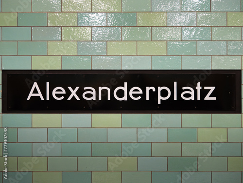Alexanderplatz station sign in Berlin. The location signage of the public transportation is part of the underground. The tiled wall is in green and teal color. photo
