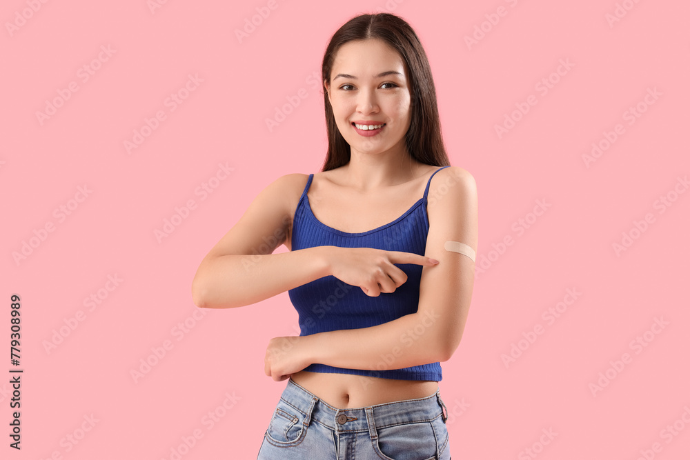 Young woman pointing at applied medical patch on her arm against color background - obrazy, fototapety, plakaty 