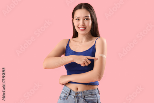 Young woman pointing at applied medical patch on her arm against color background © Pixel-Shot