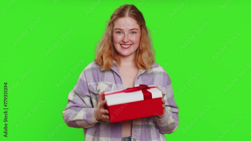 Positive smiling woman presenting birthday gift box stretches out hands, offer wrapped present career bonus, celebrating party, promotion discount sale. Redhead girl isolated on chroma key background Positive smiling woman presenting birthday gift box stretches out hands, offer wrapped present career bonus, celebrating party, promotion discount sale. Redhead girl isolated on chroma key background