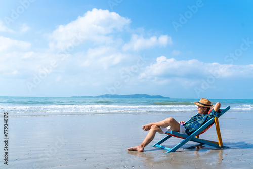 Happy Asian man relax and enjoy outdoor lifestyle travel ocean on summer holiday vacation. Handsome guy relaxing and sleeping on sunbed at tropical island beach in sunny day. People and nature concept