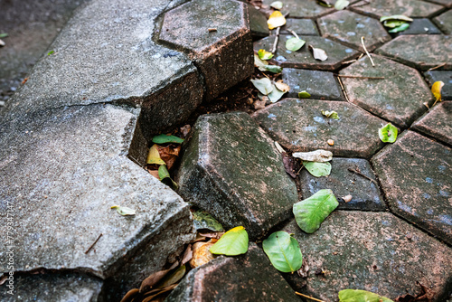 Pavement surface is damaged and dangerous. Broken brick blocks can pose danger to pedestrians. Old hexagonal brick blocks that collapse to create different level floor. Damaged and dirty brick blocks.