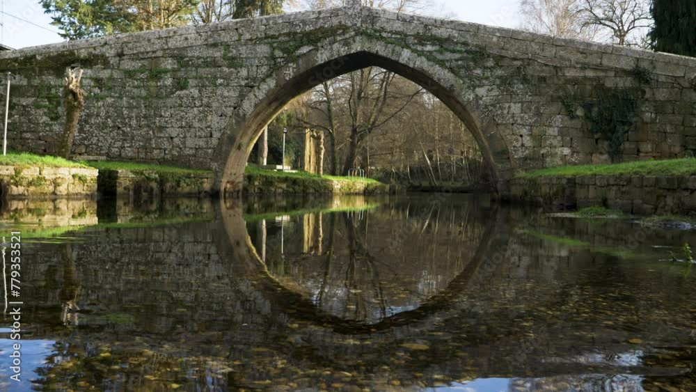 Serene bridge reflection in shallow river water below medieval roman bridge in Spanish Countryside Serene bridge reflection in shallow river water below medieval roman bridge in Spanish Countryside