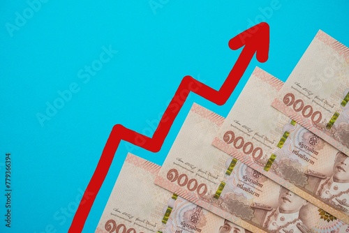 Thai thousand 1000 Baht banknotes with growth chart graph on blue background with copy space. Thailand or Asia business, economy, financial and investment concept.