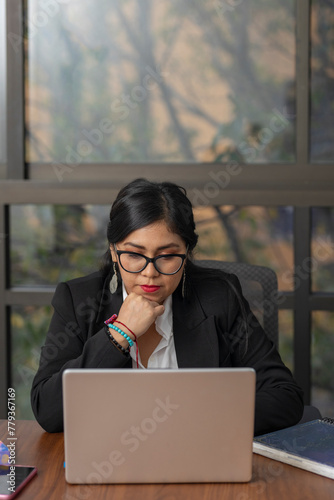 Business woman looking seriously at laptop screen while thoughtful.