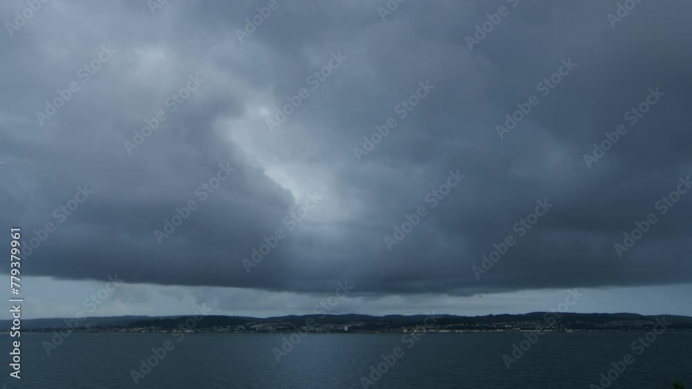 Heavy dark clouds over seaside town and water. Heavy dark clouds over seaside town and water.