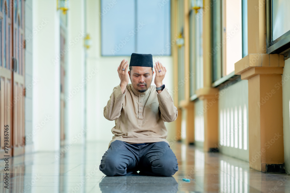 Fototapeta premium Ramadan, Muslim, Isalam, An Asian Muslim man is praying with peace in the beautiful mosque, giving a powerful atmosphere of faith, with copy space, Islam concept.