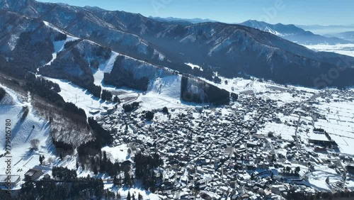 Aerial establishing shot of Japans Nozawaonsen Mountain Ski Resort Village. Camera slowly ascends and pans down revealing the mountain village resort. Clear Winter Day photo