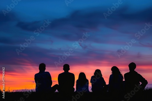 Silhouettes of people against a vibrant sunset sky.