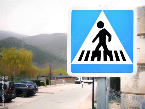 Pedestrian crossing sign on a village street. Blue square traffic sign with a person on a crosswalk