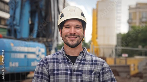Confident construction site worker portrait. Smile constructor man look at camera. Builder engineer wear white helmet. Real estate agent plaid shirt. Guy build new house city street Erector person job