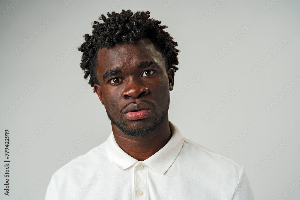 Young African American Man in White Shirt Expressing Confusion in Studio Young African American Man in White Shirt Expressing Confusion in Studio