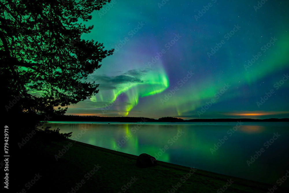 Northern lights dancing over calm lake in north of Sweden