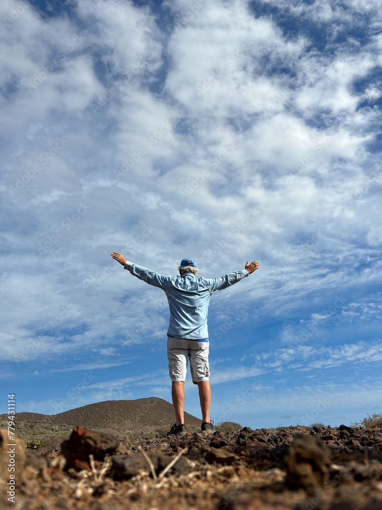 Outdoor activity in nature concept. Rear view of senior sporty man walking with open arms enjoying beautiful landscape and blue sky, healthy lifestyle Outdoor activity in nature concept. Rear view of senior sporty man walking with open arms enjoying beautiful landscape and blue sky, healthy lifestyle