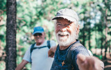 Happy senior couple of men smiling enjoying a mountain hike in the forest appreciating leisure and freedom, active cheerful retired seniors and healthy lifestyle concept