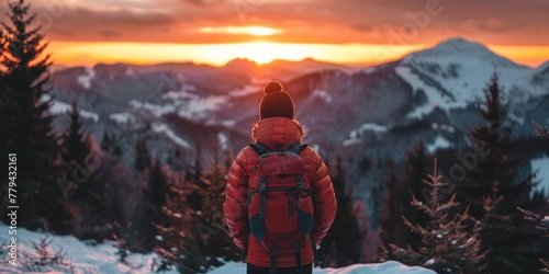 An adventurer in a red jacket contemplates a snowy mountain landscape at sunset.