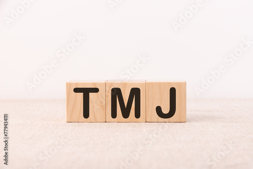 TMJ - acronym from wooden blocks with letters, abbreviation TMJ temporomandibular joint syndrome, TMD Temporomandibular disorder concept.