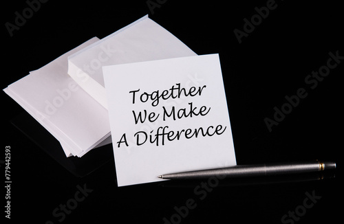 Conceptual hand writing Together we make the difference message on a white sticker with pen on a black table. photo