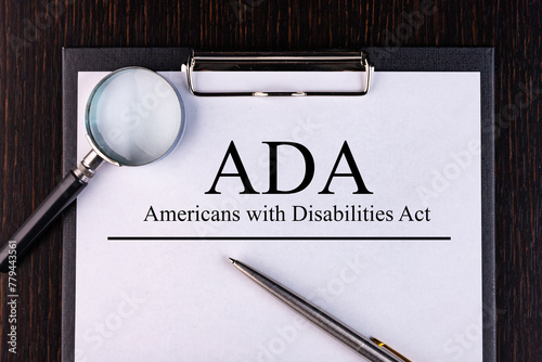 Text ADA Act. is written on a notebook with a pen and a magnifying glass lying on the table. Business concept. photo