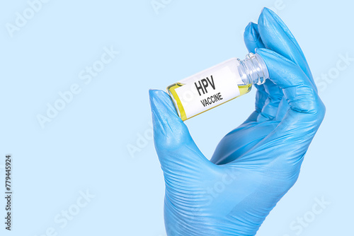 HPV VACCINE text is written on a vial whose ampoule is held by a hand in a medical disposable glove. Medical concept. photo