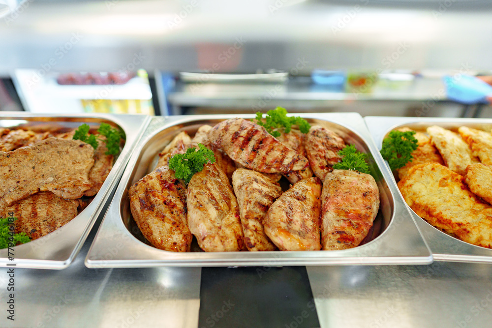 Obraz premium Grilled Chicken Breasts and Pork Cutlets Served in a Buffet Setting