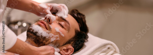 A relaxing moment at the spa portrayed with a man receiving a facial treatment, his face covered in foam, evoking a sense of calm and personal care. Banner. Copy space photo