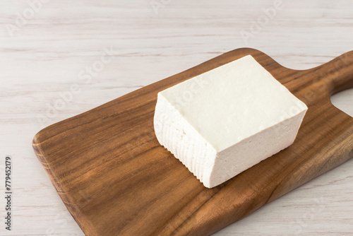 A loaf of tofu on a brown cutting board