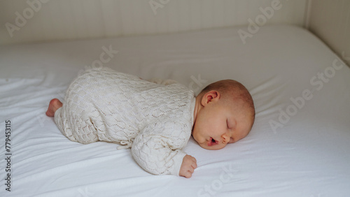 Portrait of cute little baby sleeping in bed, on belly, closed eyes.