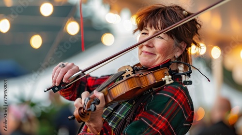 A humorous female performer in traditional Scottish attire plays the violin.