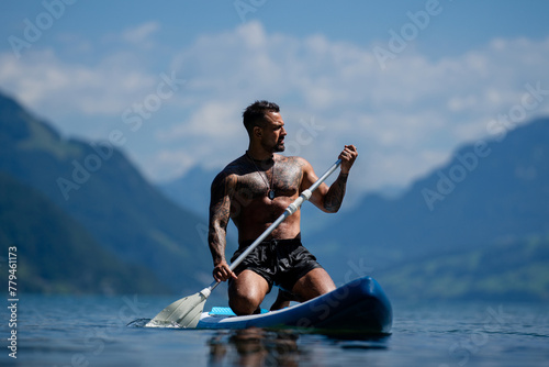 Sexy man with paddle board. Man paddling on paddleboard. Muscular strong Hispanic man on sup board paddle surfing. SUP surfing in summer vacation in lake. Strong muscular wet body. Bare naked torso.