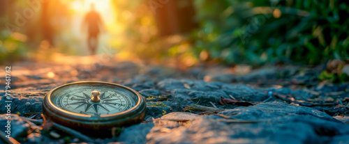 A compass lies on the forest floor, surrounded by trees and fallen leaves, indicating the direction among nature. Travel and sports tourism in the mountains. Banner. Copy space